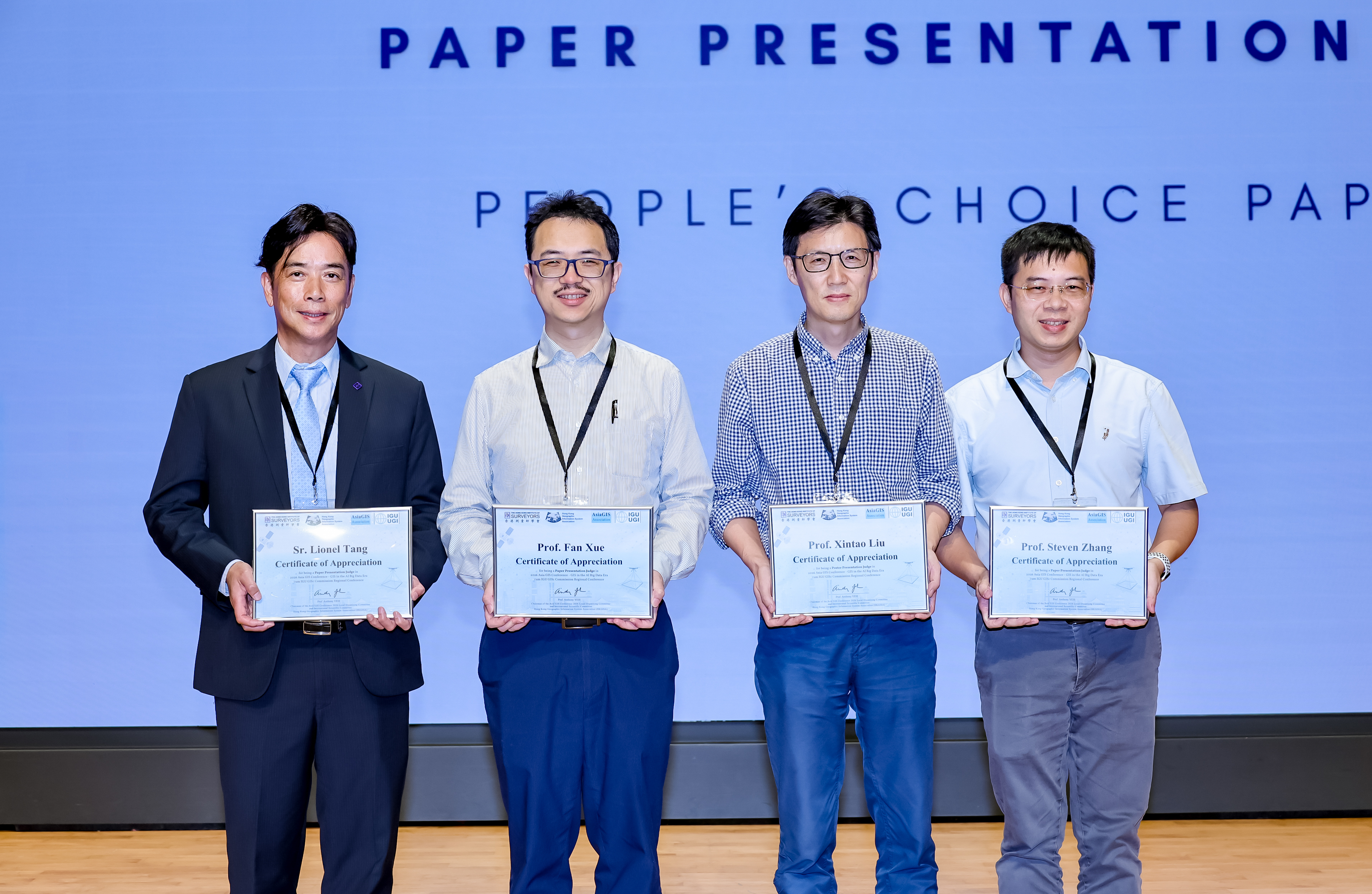 Four participants holding certificates at an academic event